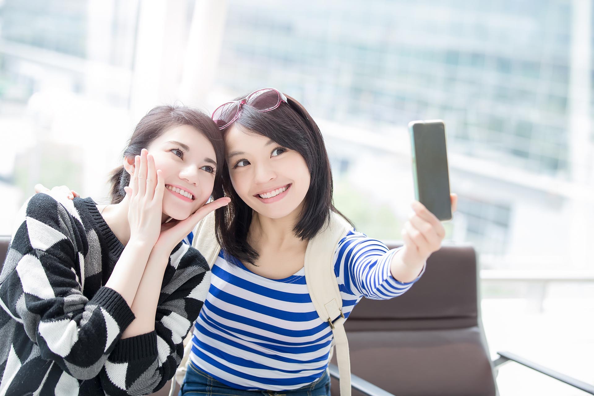 two beauty woman take smart phone and selfie in hong kong airport, asian